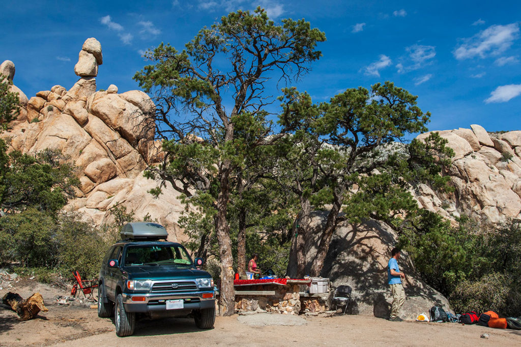 4runner beside a copse of scraggly trees and a stone picnic table, with boulders behind